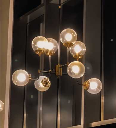 Thüraia's custom pendant lights illuminating the entrance hall of TGIF Dubai, creating a golden pathway glow above the walkway