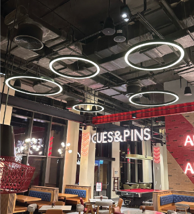 Vibrant TGIF restaurant interior at Rove Hotel Dubai featuring custom Thüraia pendant lights and American-style bar area with warm ambient lighting
